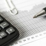 Close-up of a calculator and pen on a bar graph, representing finance and accounting.